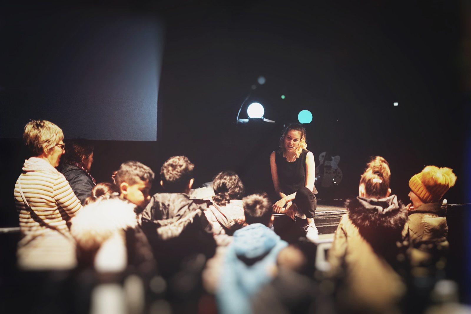 Atelier d'ombres : Ladylike Lily échange avec un groupe d'enfants devant la scène