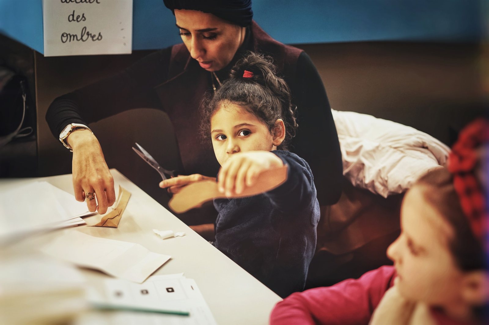 Atelier des ombres : une enfant montre sa marionnette découpée